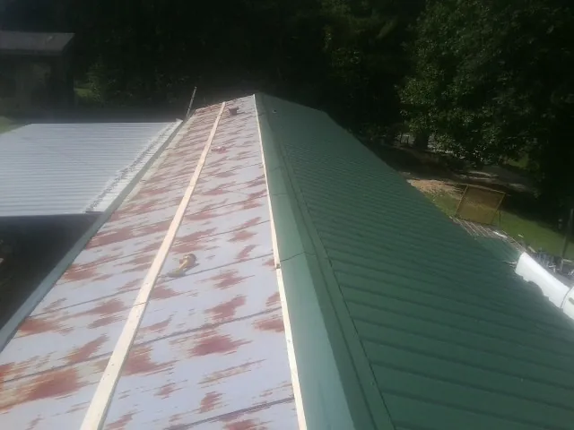 Old rusted panels beside newly installed green metal roofing — Wind Damage Roof Repair by Roofing Brothers in Betterton