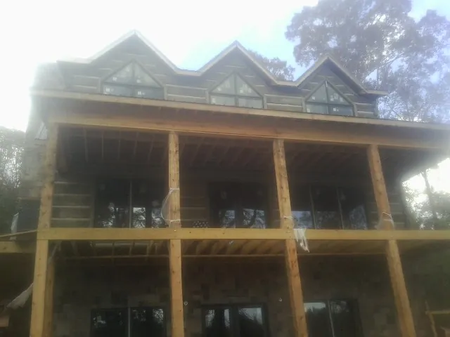 Dormers and porch framing on a large log home under construction — Roof Coating work by our crew in Betterton