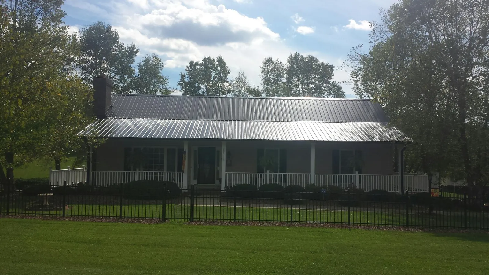 Gray metal roof on a brick ranch with a full width front porch — Gutter Guard Installation work by our crew in Betterton