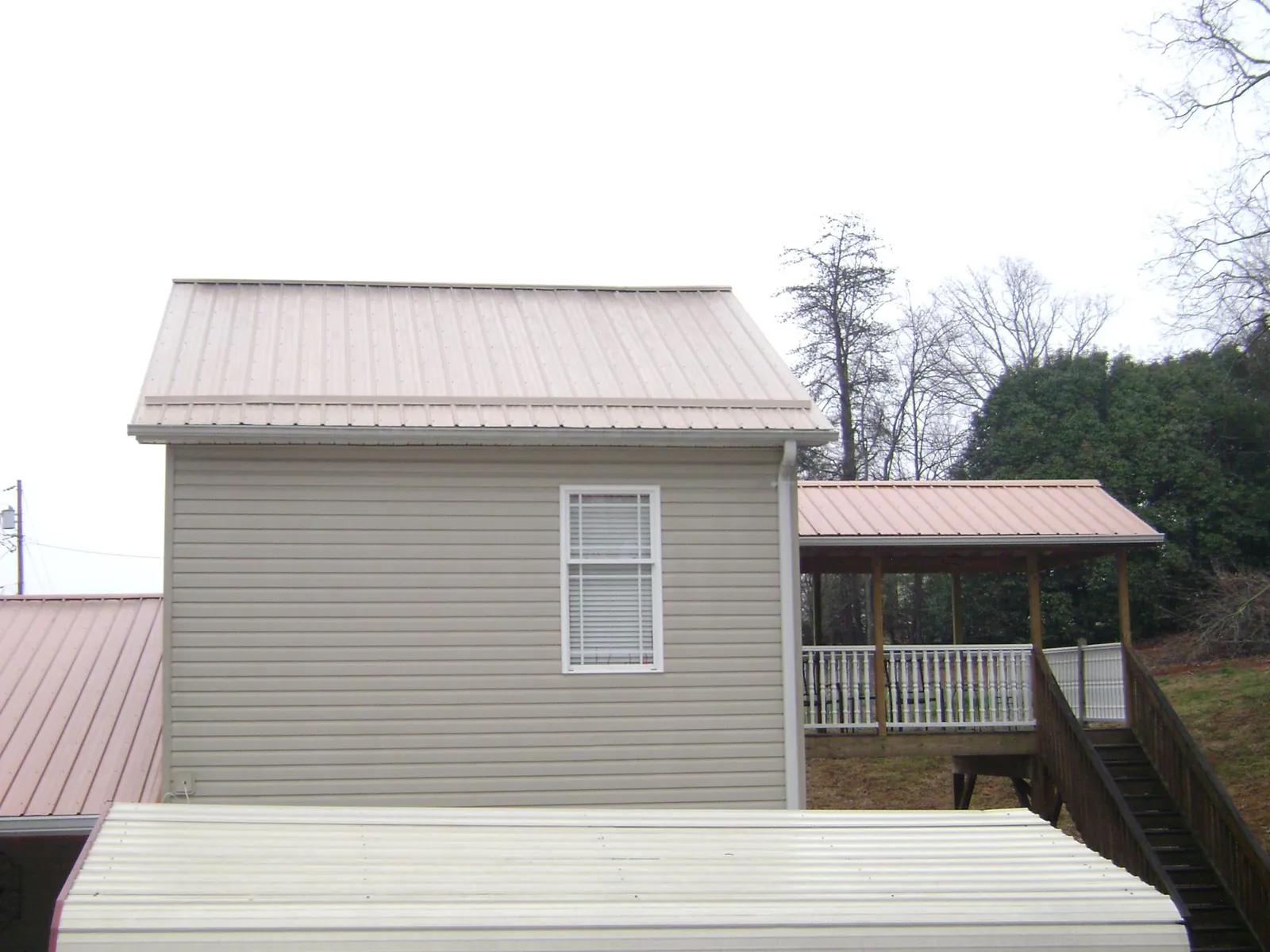 Tan metal roofs on a two story addition and attached porch, from a Roof Replacement job in Betterton