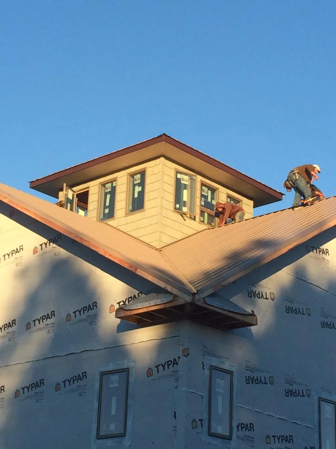 Roofers working around a rooftop cupola on a new metal roof at sunset — Roof Waterproofing in Betterton by Roofing Brothers